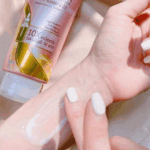 Close-up of Vaseline Healthy Bright Gluta-Hya Dewy Radiance lotion being applied on the wrist, showing a lightweight, milky serum texture with a pink Vaseline Gluta-Hya tube in the background.