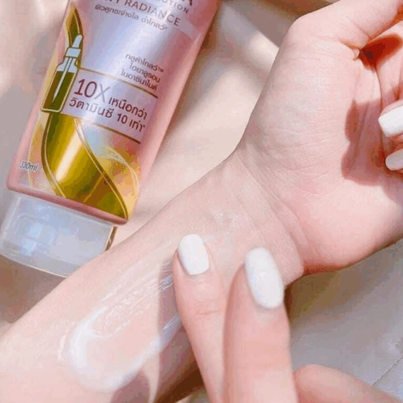 Close-up of Vaseline Healthy Bright Gluta-Hya Dewy Radiance lotion being applied on the wrist, showing a lightweight, milky serum texture with a pink Vaseline Gluta-Hya tube in the background.
