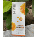 Dr. Rashel Vitamin C face serum box placed outdoors against green leaves, featuring orange slice graphics and Vitamin C icons, highlighting a brightening and anti-aging formula with hyaluronic acid in natural daylight.