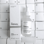 The Ordinary Alpha Arbutin 2% + HA serum bottle and box on stacked boxes background
