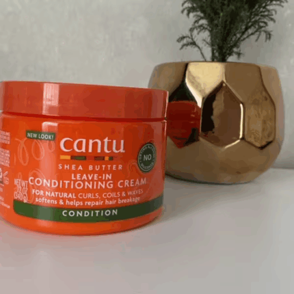 Cantu Shea Butter Leave-In Conditioning Cream jar placed on shelf with decorative plant