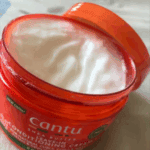 Open Cantu Shea Butter Leave-In Conditioning Cream jar showing creamy texture inside