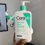 Hand holding CeraVe Foaming Facial Cleanser 355ml pump bottle indoors