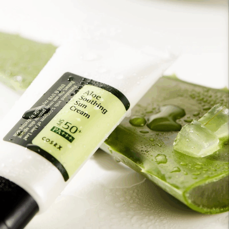 COSRX Aloe Soothing Sun Cream SPF 50+ placed on fresh aloe vera leaf showing hydrating sunscreen texture