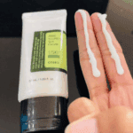 COSRX Aloe Soothing Sun Cream SPF 50+ sunscreen texture applied on fingers next to product tube