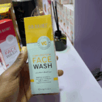 Hand holding Dr. Rashel Vitamin C brightening face wash box inside a cosmetics store