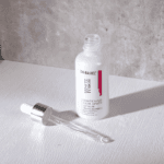 Open Dr. Rashel Whitening Fade Spots Serum bottle with glass dropper placed beside it, highlighting liquid serum texture.