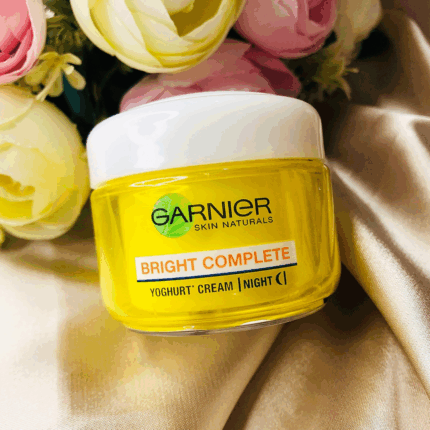 Garnier Bright Complete Vitamin C yoghurt night cream in yellow jar with white lid on soft fabric background