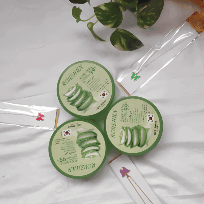 Flat lay view of Roushun Aloe Vera 99% soothing moisturizing gel tubs arranged on a white background with green leaves.