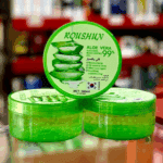 Roushun Aloe Vera 99% soothing moisturizing gel tubs stacked on a store counter with blurred retail shelves in the background.