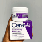 Hand holding CeraVe Skin Renewing Night Cream box with the cream jar placed on top