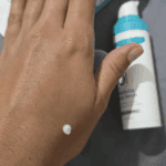 CeraVe Resurfacing Retinol Serum cream texture applied on hand with serum bottle in background