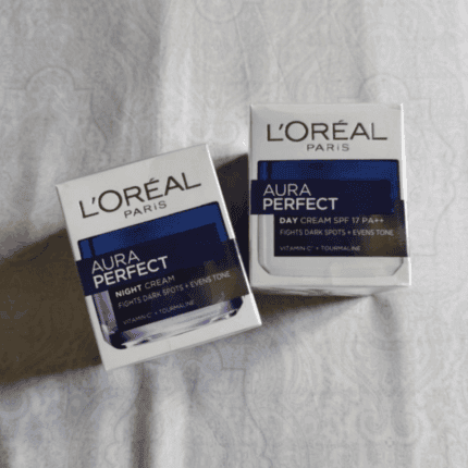 L’Oréal Paris Aura Perfect Day Cream and Night Cream boxes placed side by side on a light fabric background