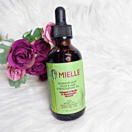 Mielle Rosemary Mint Scalp and Hair Strengthening Oil bottle placed on white fur background with purple roses