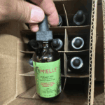 Mielle Rosemary Mint Scalp and Hair Strengthening Oil bottle taken from cardboard box with multiple bottles inside