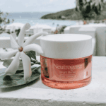 Neutrogena Bright Boost gel cream placed outdoors with white flower and ocean view in background