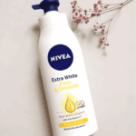 NIVEA Extra White Firm and Smooth body lotion laid flat with pump top and decorative dried flowers