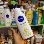 Hand holding NIVEA Extra White Firm and Smooth body lotion in a cosmetic store shelf background