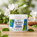 St. Ives Renewing Moisturizer with Collagen and Elastin placed on a wooden surface with green leaves and flowers