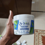 Hand holding St. Ives Renewing Moisturizer Collagen and Elastin tub indoors