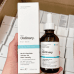 Hand holding The Ordinary Multi-Peptide Serum for Hair Density bottle next to its box
