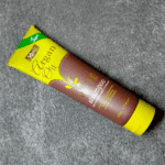 XHC Argan Oil shampoo tube placed diagonally on a grey textured fabric surface