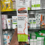 Palmer’s Cocoa Butter Formula Stretch Marks Massage Cream box held in hand showing collagen, elastin, argan oil, and shea butter