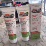 Stretch marks massage cream tubes and box packaging with cocoa butter, collagen, shea butter, and argan oil on tabletop