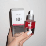 Hand holding Anua Niacinamide 10% TXA 4% serum bottle with box in natural lighting