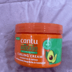 Cantu avocado hydrating curling cream jar with new look label on fabric background