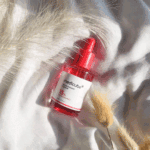 Medicube TXA Niacinamide 15 Serum 30ml with 15% TXA + Niacinamide in pink bottle placed on soft white fabric background