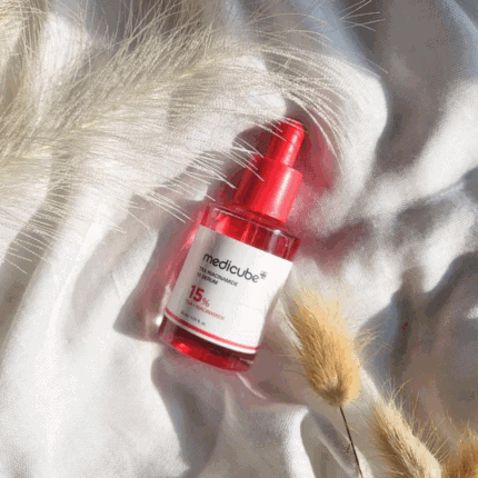 Medicube TXA Niacinamide 15 Serum 30ml with 15% TXA + Niacinamide in pink bottle placed on soft white fabric background