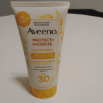 Aveeno Protect + Hydrate SPF 30 sunscreen tube with broad-spectrum UVA/UVB protection and all-day hydration on a white background.