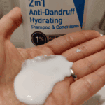 Close up of CeraVe 2 in 1 Anti Dandruff Hydrating Shampoo texture on hand, creamy formula with pyrithione zinc for flake removal and scalp care.