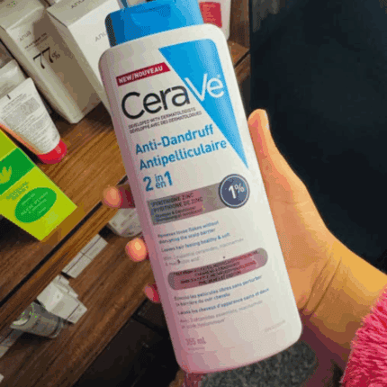 Hand holding CeraVe Anti Dandruff 2 in 1 shampoo 355ml with pyrithione zinc, helps remove flakes and protect scalp barrier for healthy hair.