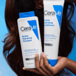 A person holding CeraVe Gentle Hydrating Shampoo and Gentle Hydrating Conditioner bottles in front of long, healthy hair against a blue background, highlighting gentle cleansing and conditioning benefits for hair and scalp.