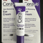 A tube of CeraVe Skin Renewing Eye Cream placed in front of two product boxes, highlighting features like reducing fine lines, moisturizing, and peptide complex, against a dark background.