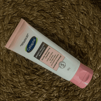 Cetaphil Bright Healthy Radiance Gentle Renewing Cleanser 100g tube placed on woven mat, brightening face wash for sensitive skin that purifies and refines skin texture.