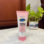 Cetaphil Bright Healthy Radiance Gentle Renewing Cleanser 100g tube placed on soft surface with plant background, brightening face wash that purifies and refines skin texture for radiant skin.