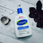 Cetaphil Daily Facial Cleanser bottle for combination to oily sensitive skin, fragrance free face wash with hydrating glycerin placed on wooden surface with decorative elements.