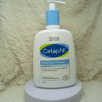 Cetaphil Gentle Skin Cleanser 500ml bottle placed on a white stand with soft fabric background, soap free gentle cleanser for dry to normal sensitive skin.