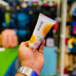 Hand holding Dr Rashel Vitamin C Facial Cleanser tube with orange extract, brightening and anti aging face wash with hyaluronic acid for glowing skin.
