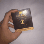 A hand holding the box of Dr. Rashel 24K Gold Collagen Anti-Wrinkle Gel Cream, featuring black and gold packaging, shown against a plain background.