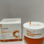 A jar and box of Dr. Rashel Vitamin C Brightening and Moisturizing Body Butter displayed together with text highlighting benefits like enhancing skin tone and smoothing the skin, set against a neutral background.