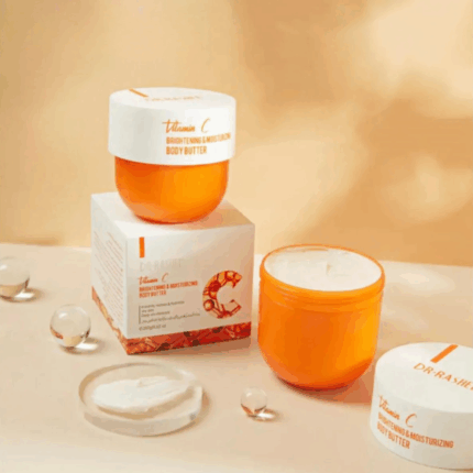 Multiple jars of Dr. Rashel Vitamin C Brightening and Moisturizing Body Butter displayed with packaging, including an open jar showing the cream texture, arranged with decorative elements on a soft beige background.