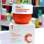 A jar of Dr. Rashel Vitamin C Exfoliating and Brightening Face and Body Scrub placed on top of its box, with a blurred retail shelf background, highlighting its exfoliating and skin-brightening benefits.