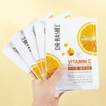 Multiple Dr. Rashel Vitamin C Brightening and Anti-Aging Silk Mask sachets arranged on a beige surface with decorative orange slices and a woven mat, highlighting the citrus-themed packaging and skincare benefits.