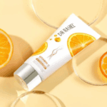 Dr. Rashel Vitamin C whitening cream tube placed on a soft beige background with sliced oranges, highlighting brightening and skincare benefits.