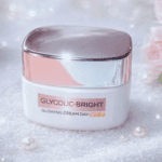 Glycolic-Bright Glowing Cream Day SPF 17 brightening moisturizer in a white jar with a reflective silver lid on a soft sparkling background with pearls.