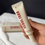 Hand holding K-Secret Seoul 1988 Eye Cream 30ml tube with product box in the background.